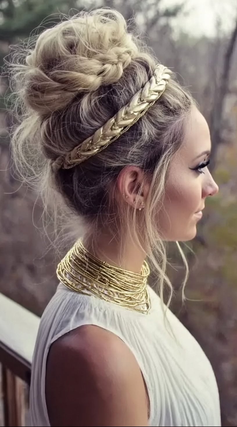 Side profile of a woman with a high braided bun, loose strands framing her face, and a thick gold rope-style headband.