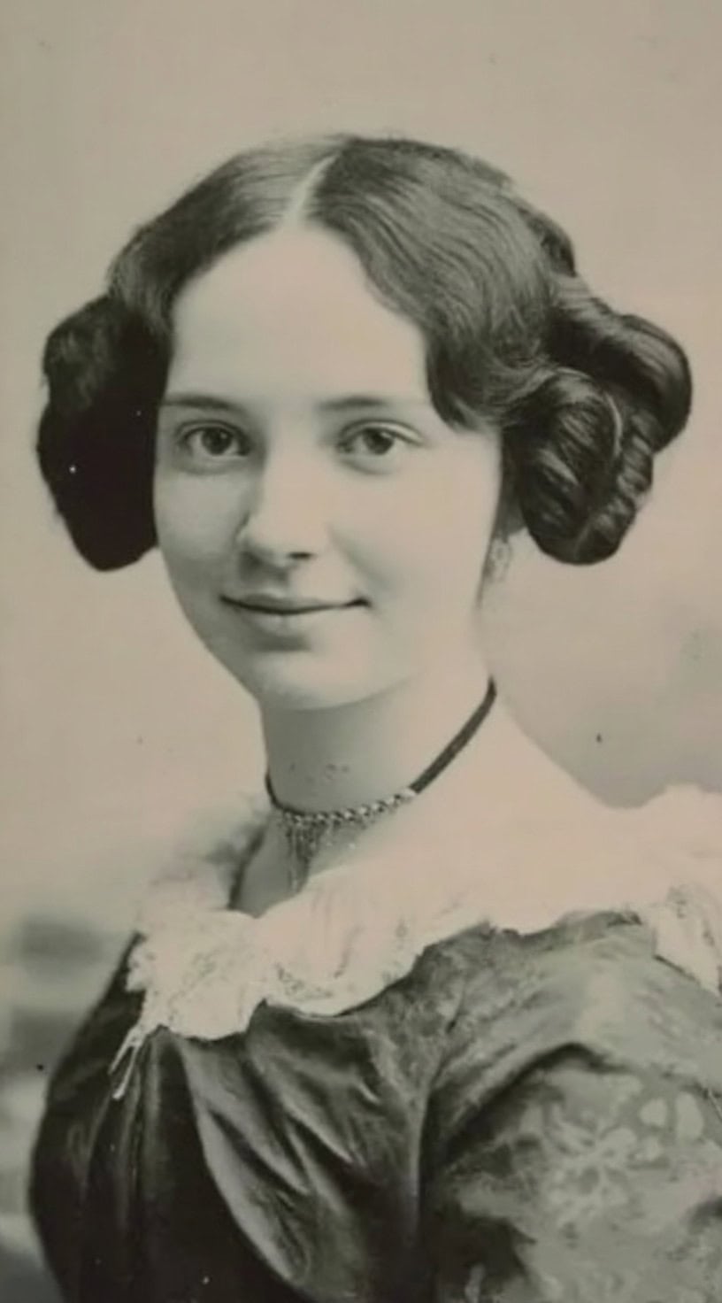 Young woman with dark hair in softly textured side loops and a center part, wearing a delicate lace collar.